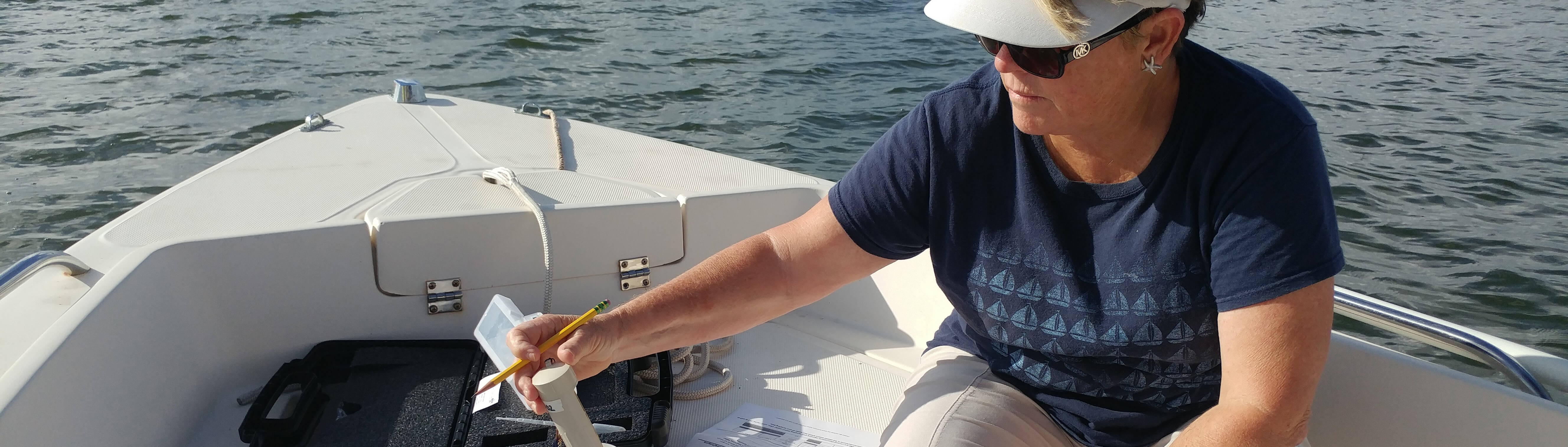 photo of a water watch volunteer collecting a sample in a boat 