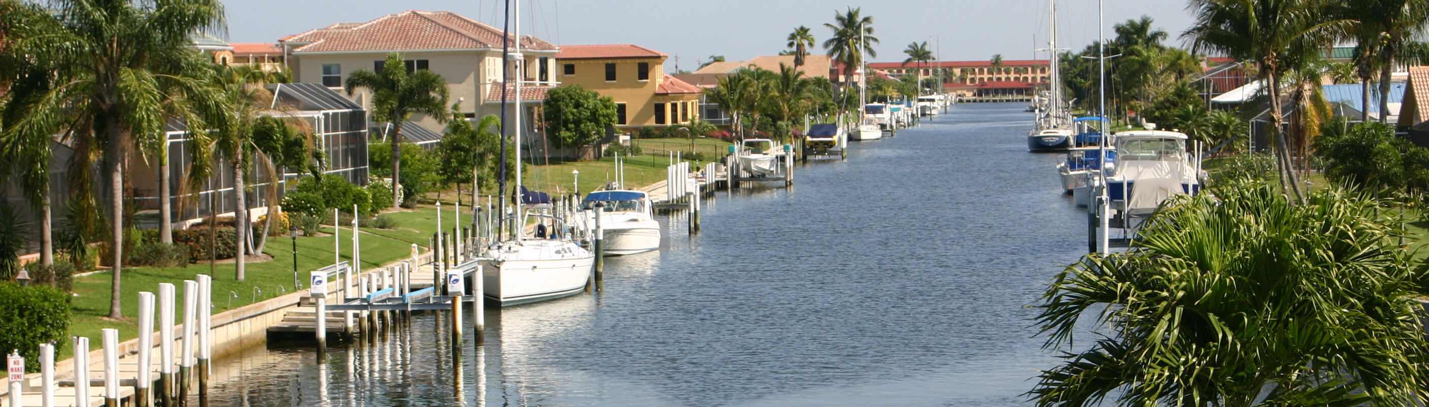 photo of a canal with with boats and large houses on each side