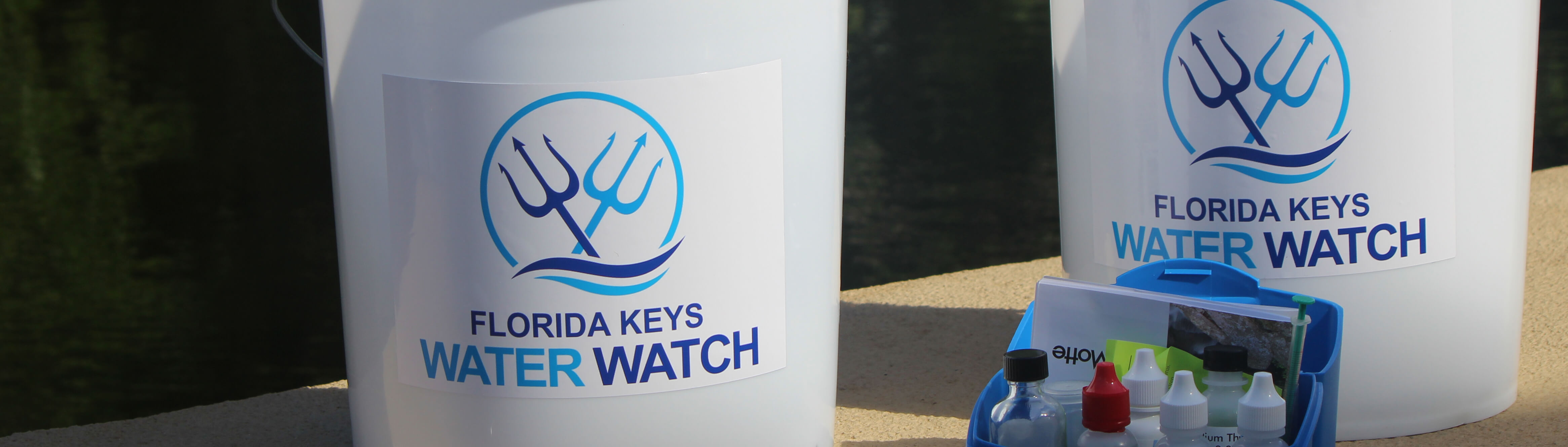 photo of two white buckets labeled Florida Keys Water Watch, with scientific equipment in the foreground